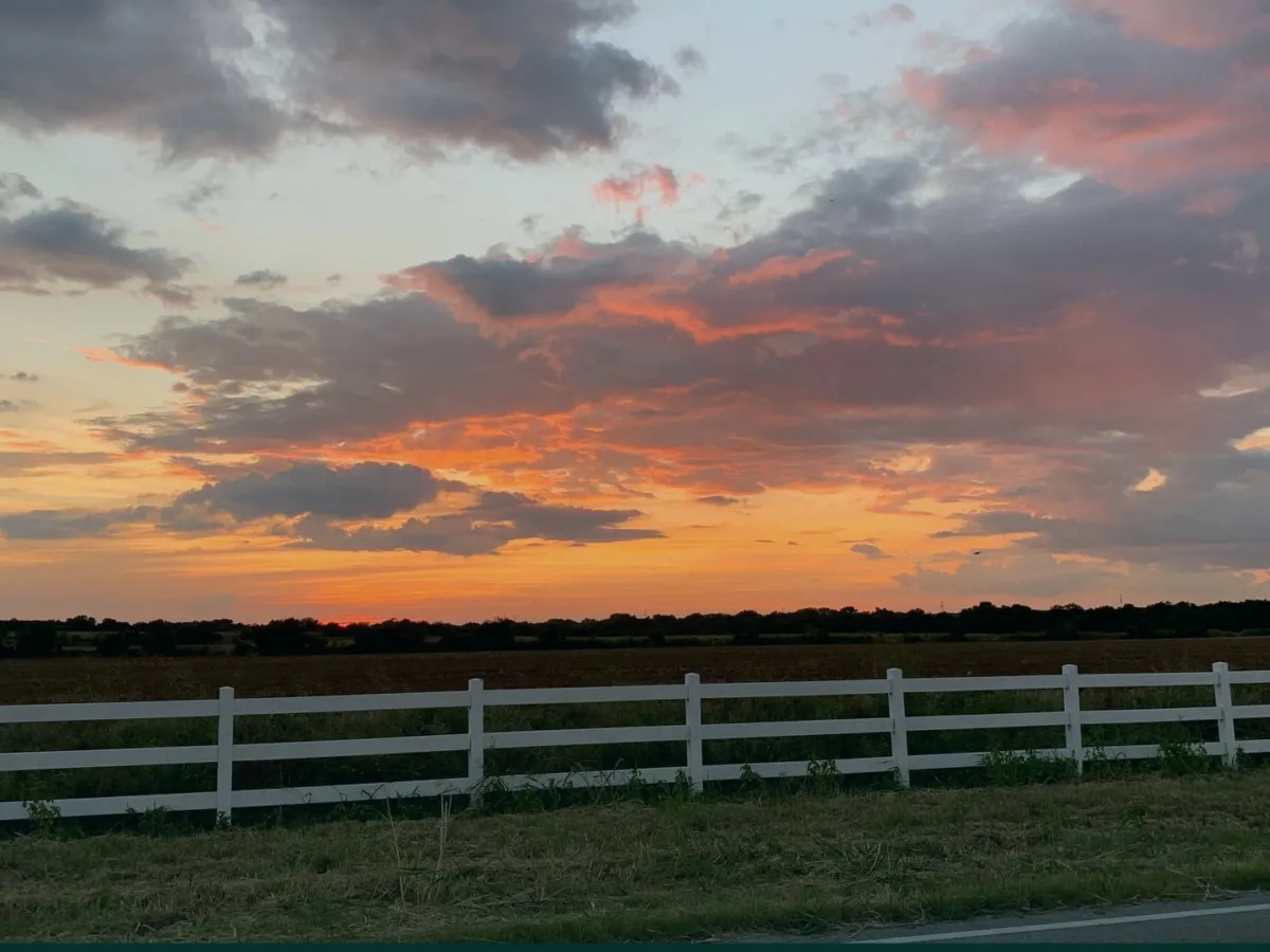 Sunset over a Texas pasture with a white fence